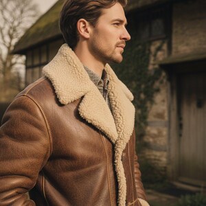 Peut inclure: Veste en cuir marron avec un col et une doublure en peau de mouton cr&egrave;me. La veste a un design classique avec une fermeture &agrave; boutons et une finition textur&eacute;e. La personne porte une chemise &agrave; motifs sous la veste.