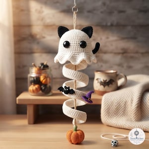 May include: A hanging crochet decoration featuring a white ghost-like cat with black ears and eyes, attached to a white spiral tail. The spiral is adorned with a small black bat and a purple witch hat, ending with an orange crochet pumpkin at the base.