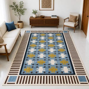 Puede incluir: Una alfombra rectangular con un campo azul claro y un patrón geométrico repetitivo de formas de cruz en color amarillo mostaza y blanco. El borde consta de rayas de color marrón oscuro y blanco con cuadrados azules en las esquinas.
