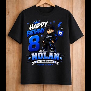 May include: Black t-shirt with a blue and white graphic design. The design includes the words "Happy Birthday" and "Nolan", along with the number "8" and a Roblox character. The shirt also says "8 years old" and "Born to Win".