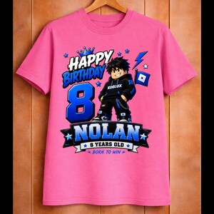 May include: A pink t-shirt with a graphic design for an 8th birthday. The design includes the words "Happy Birthday," the number "8" in blue, and the name "Nolan." A Roblox character is featured in the center.
