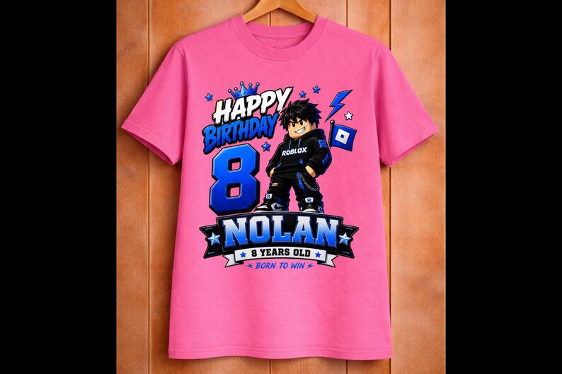 May include: A pink t-shirt with a graphic design for an 8th birthday. The design includes the words "Happy Birthday," the number "8" in blue, and the name "Nolan." A Roblox character is featured in the center.