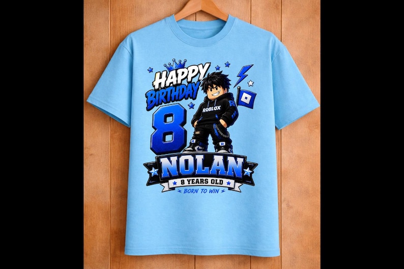 May include: Light blue t-shirt with a graphic design for an 8-year-old's birthday. The design includes the text "Happy Birthday," the number "8," the name "Nolan," and a Roblox character. The shirt also says "9 years old" and "Born to Win."