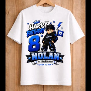 May include: White t-shirt with a blue and black graphic design. The design includes the words "Happy Birthday" above a large blue number "8", the name "Nolan", and the phrase "8 Years Old Born to Win". A cartoon character is also featured.