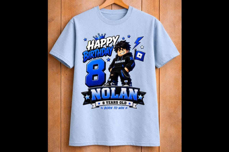 May include: Light blue t-shirt with a graphic design for an 8th birthday. The design includes the words "Happy Birthday," the number "8" in blue, and the name "Nolan." A cartoon character is also featured.