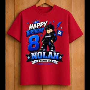 May include: Red t-shirt with a graphic design for an 8th birthday. The design includes the words "Happy Birthday" and "Nolan 8 Years Old" in blue and white, along with a cartoon character and Roblox logo.