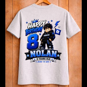 May include: A light gray t-shirt featuring a graphic design for an 8th birthday. The design includes the words "Happy Birthday" and "Nolan", along with a cartoon character and the text "8 Years Old".