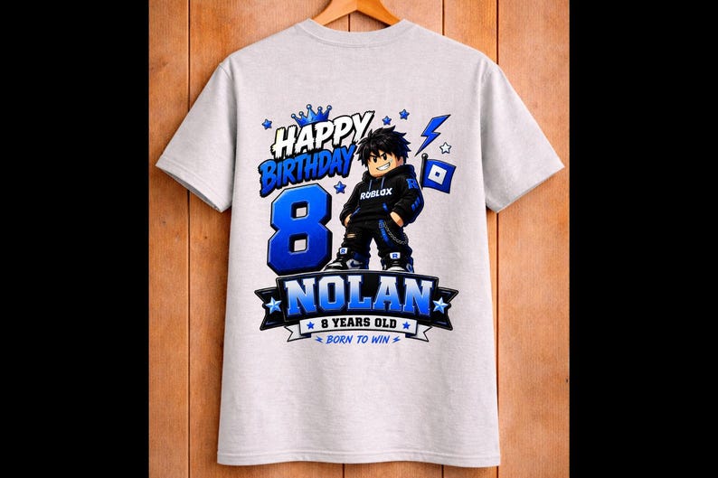 May include: A light gray t-shirt featuring a graphic design for an 8th birthday. The design includes the words "Happy Birthday" and "Nolan", along with a cartoon character and the text "8 Years Old".