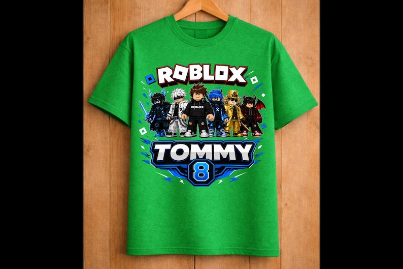 May include: Green t-shirt featuring the word "ROBLOX" in white and red, with a group of cartoon characters. Below, the name "TOMMY" and the number "8" are displayed in a blue and white design. The shirt is hanging on a wooden hanger.