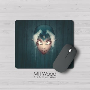 Peut inclure: Un tapis de souris bleu foncé et vert avec une illustration stylisée d'un personnage aux cheveux blancs et un masque bleu. Le personnage a un cœur blanc sur le front et des marques rouges sur le visage. Le tapis de souris a une texture en bois et le texte "Mtt Wood Art & Illustration" est imprimé en bas.