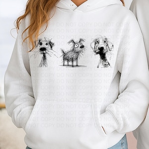 May include: White hooded sweatshirt featuring a whimsical illustration of three sketched dogs. The dogs are depicted in a black, scribbled style, each with unique expressions. The sweatshirt has a front pocket and a drawstring hood.