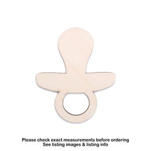 Puede incluir: Recorte de madera con forma de chupete, con una parte superior redondeada, un escudo plano y un asa de anillo. El color natural de la madera proporciona una base neutra para la artesanía o la decoración. El texto en la parte inferior dice "Por favor, compruebe las medidas exactas antes de realizar el pedido".
