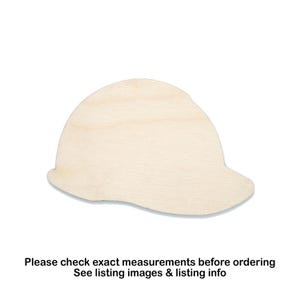May include: A light-colored, wooden hard hat cutout. The hat is a light tan color and has a curved brim. The text at the bottom of the image reads: "Please check exact measurements before ordering. See listing images & listing info."