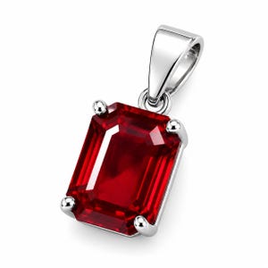 May include: A rectangular emerald-cut red gemstone pendant set in a polished silver-toned metal prong setting. The pendant features a smooth, reflective bail at the top, designed to hold a chain, with a vibrant, deep red faceted stone as the centrepiece.