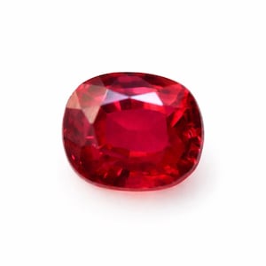 Peut inclure: Un rubis de forme coussin, d'un rouge profond et intense. La pierre précieuse présente de multiples facettes qui réfléchissent la lumière. Le rubis est posé sur un fond blanc, mettant en valeur son éclat.
