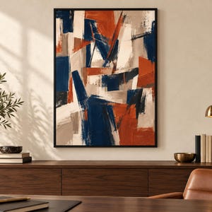 Könnte beinhalten: Ein rechteckiges Wandbild mit einer abstrakten Komposition aus kräftigen, überlappenden Pinselstrichen in tiefem Marineblau, gebranntem Orange und cremigen Beigetönen, eingefasst in einen dünnen schwarzen Rahmen, der den Farbauftrag betont.