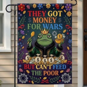 Pode incluir: Uma bandeira de jardim decorativa com um sapo de desenho animado usando uma coroa e segurando uma colher e uma tigela de moedas. A bandeira tem o texto "THEY GOT MONEY FOR WARS BUT CAN'T FEED THE POOR" rodeado por desenhos florais e de engrenagens.