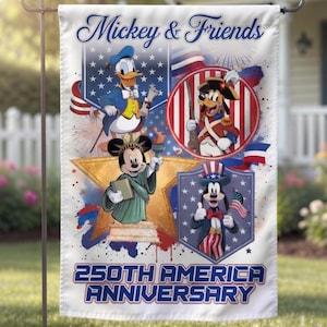 May include: A white garden flag featuring Mickey & Friends celebrating the 250th American Anniversary. The flag has illustrations of Mickey Mouse, Donald Duck, and Goofy in patriotic attire, with fireworks and American flag imagery.
