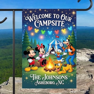 May include: A rectangular garden flag hanging on a black metal stand, featuring Mickey Mouse, Minnie Mouse, Donald Duck, Goofy, and Pluto camping by a fire. The text reads Welcome to Our Campsite, The Johnsons, and Asheboro, NC, under starry skies.