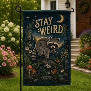 May include: A rectangular garden flag featuring a dark blue night sky with a crescent moon and stars. A raccoon stands on a rock in a forest with mushrooms and wildflowers. The text STAY WEIRD is printed in gold, and the name JIMOTHY is at the bottom.