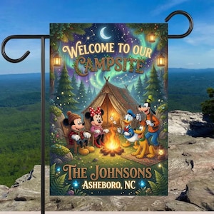May include: A rectangular garden flag featuring a nighttime camping scene with Mickey Mouse, Minnie Mouse, Donald Duck, Goofy, and Pluto around a campfire. The text reads Welcome to our Campsite, The Johnsons, and Asheboro, NC under a starry sky.