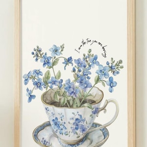 Può includere: Stampa incorniciata raffigurante una tazza e un piattino con motivi floreali blu, riempiti di fiori blu. Il testo "I am the tea you are having" è sopra la tazza.