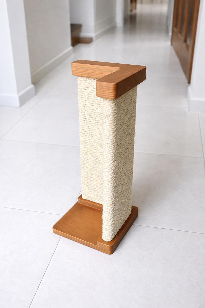 Puede incluir: Un rascador para gatos de madera con una superficie para rascar de cuerda natural. El poste tiene una base cuadrada y una pieza superior, ambas de madera de color marr&oacute;n claro. La cuerda de sisal est&aacute; enrollada alrededor de la columna central. Un dise&ntilde;o moderno de muebles para gatos.
