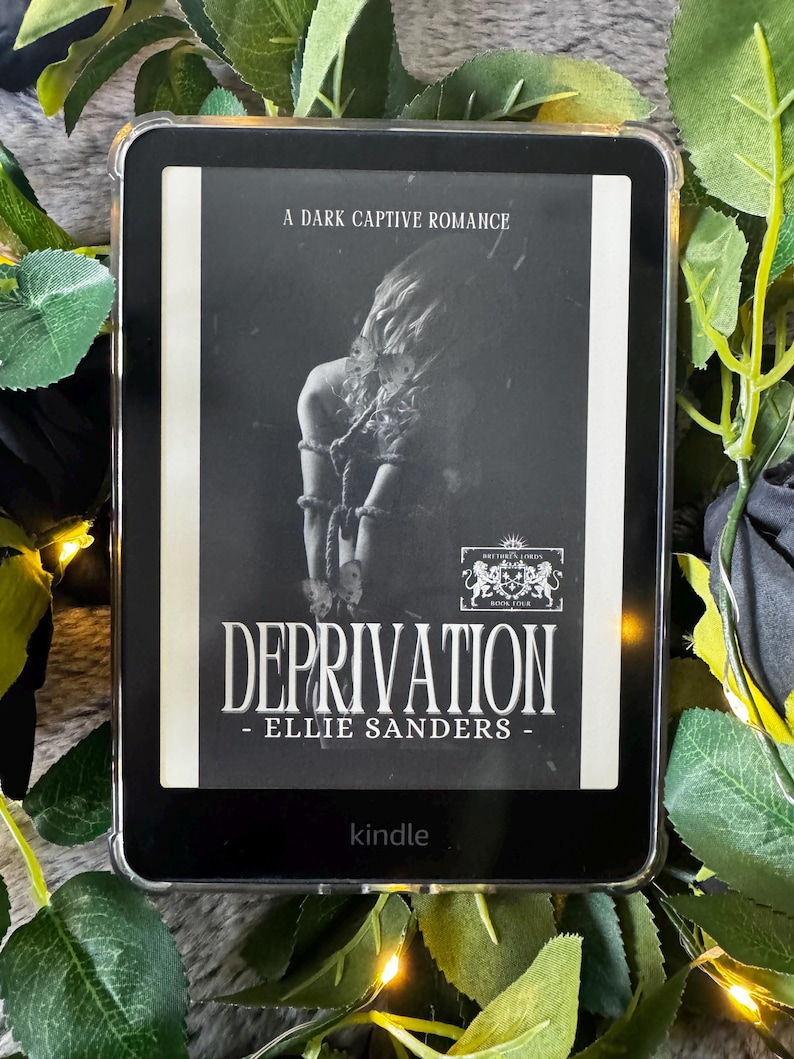 K&ouml;nnte beinhalten: Ein schwarzer Kindle-E-Reader, der das Buchcover von "Deprivation" von Ellie Sanders anzeigt. Das Cover zeigt ein Graustufenbild einer gefesselten Person. Der Text "A Dark Captive Romance" steht oben.