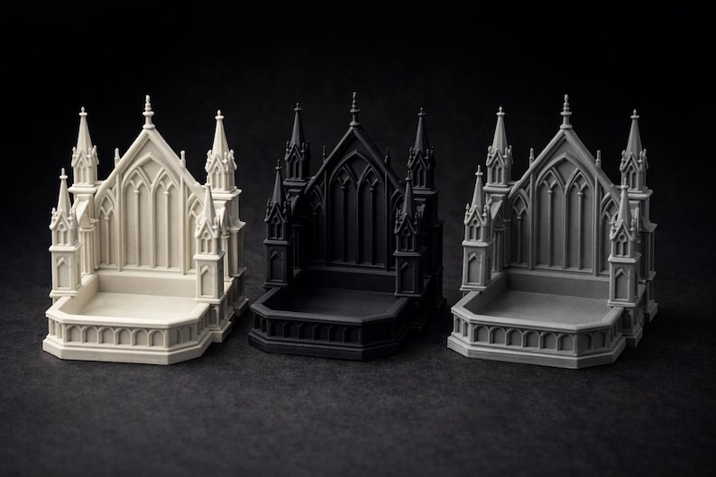 K&ouml;nnte beinhalten: Drei Miniaturmodelle gotischer Kathedralen in Off-White, Schwarz und Grau. Jedes Modell weist aufwendige architektonische Details auf, darunter T&uuml;rme, Spitzbogenfenster und einen rechteckigen Sockel. Die Modelle werden vor einem dunklen Hintergrund pr&auml;sentiert.