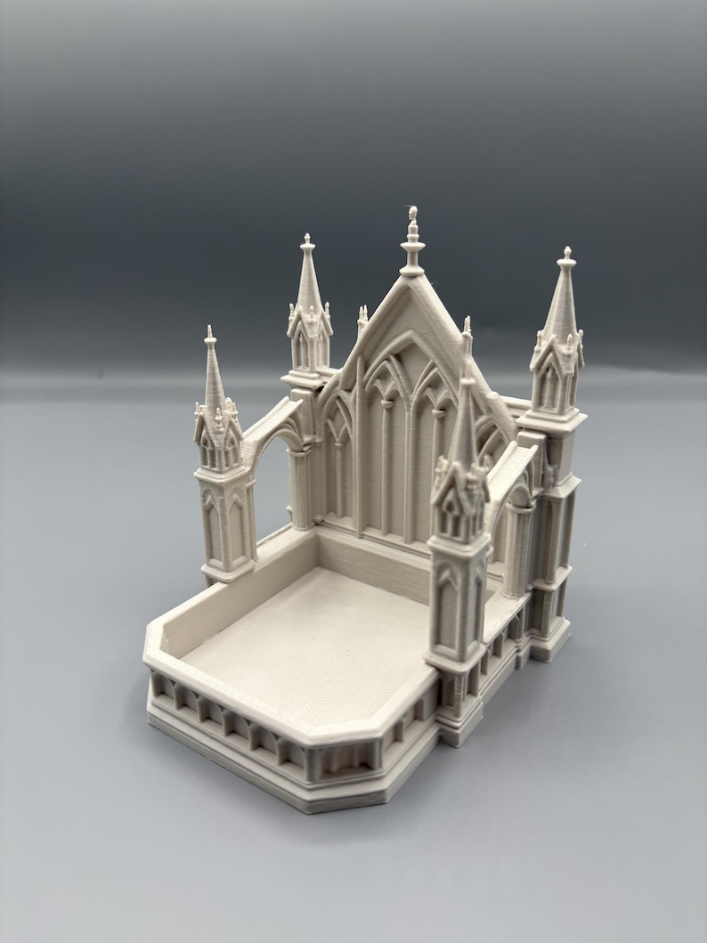K&ouml;nnte beinhalten: Hellgraues Miniatur-Kathedralenmodell mit aufwendigen architektonischen Details. Das Modell verf&uuml;gt &uuml;ber Spitzb&ouml;gen, T&uuml;rme und eine rechteckige Basis. Das Design erinnert an gotische Architektur.