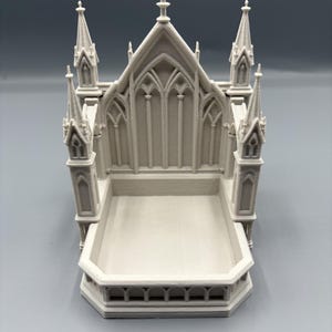 K&ouml;nnte beinhalten: Ein 3D-gedrucktes, cremefarbenes Miniatur-Kathedralenmodell. Das Modell weist detaillierte architektonische Elemente auf, darunter T&uuml;rme, Bogenfenster und eine rechteckige Basis. Das Design erinnert an gotische Architektur.