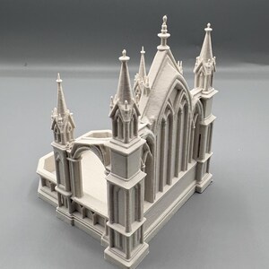 K&ouml;nnte beinhalten: Ein hellgraues Miniaturmodell einer Kathedrale mit detaillierten T&uuml;rmen, gew&ouml;lbten Fenstern und architektonischen Elementen. Das Modell hat eine rechteckige Basis und einen gew&ouml;lbten Eingang.