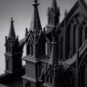 K&ouml;nnte beinhalten: Ein detailliertes, graustufiges 3D-gedrucktes Modell einer gotischen Kathedrale. Das Modell weist komplizierte architektonische Details auf, darunter T&uuml;rme, Bogenfenster und dekorative Elemente. Die dunkelgraue Farbe und die strukturierte Oberfl&auml;che verleihen ihm ein realistisches Aussehen.