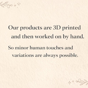 K&ouml;nnte beinhalten: Cremefarbener Hintergrund mit Text, der besagt, dass Produkte 3D-gedruckt und von Hand nachbearbeitet werden, was zu leichten Variationen f&uuml;hrt. Florale Eckendesigns in Braun umrahmen den Text.