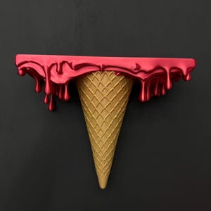 May include: A wall-mounted shelf shaped like an ice cream cone. The top flat surface features a glossy, metallic red finish with realistic drips cascading down the sides, while the base is a textured, tan-colored waffle cone shape.
