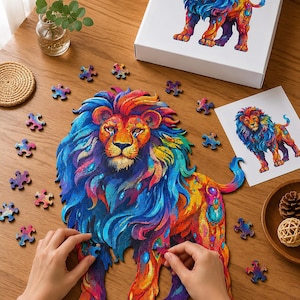 Puede incluir: Un rompecabezas con forma de león de pie con un patrón vibrante y multicolor de remolinos azules, rojos, naranjas y amarillos. El rompecabezas está parcialmente ensamblado, con piezas sueltas alrededor, una imagen de referencia y una caja.