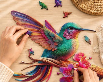 Könnte beinhalten: Ein farbenfrohes Holzpuzzle in Form eines Kolibris, der auf einem blühenden Ast sitzt. Der Vogel zeigt schillernde Töne in Türkis, Blau, Violett und Orange. Mehrere lose, individuell geformte Puzzleteile sind um das Hauptmotiv herum verstreut.