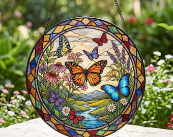 Peut inclure: Un capteur de soleil circulaire en vitrail représentant un paysage vibrant avec une rivière bleue sinueuse, des collines vertes et divers papillons colorés, dont un grand monarque orange, un papillon bleu et un machaon jaune parmi les fleurs.