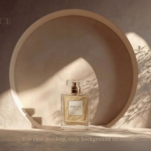 May include: A rectangular perfume bottle with a gold cap and a label that reads "PERFUME". The bottle is set against a beige circular backdrop with a textured surface. The image is lit with natural light, creating shadows.