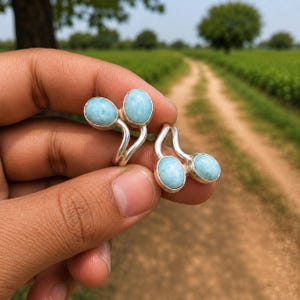 May include: Two silver rings, each featuring two oval-shaped, light blue Larimar gemstones. The rings have an open, bypass-style band design where the stones are set at the ends of the silver metal, creating a symmetrical, dual-stone appearance.