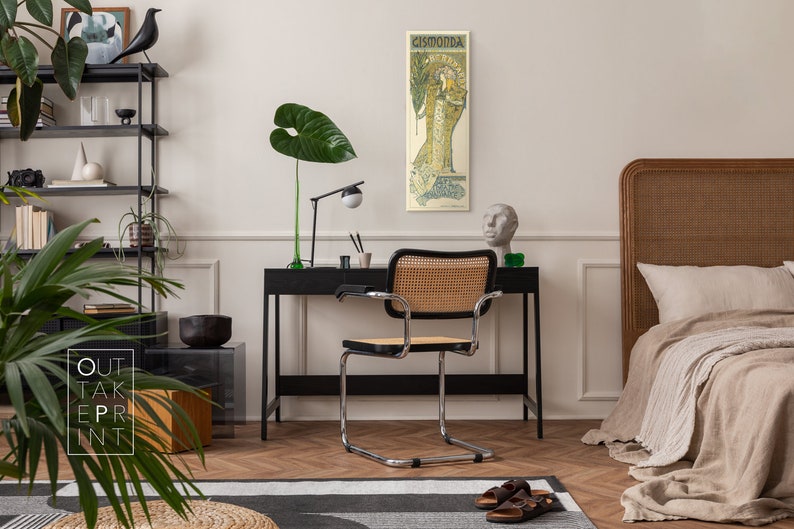 May include: A black and white poster with the text "Cismonda" in a decorative font. The poster features a woman in a long, flowing dress with a floral design. The poster is hanging on a white wall in a room with a black desk, a chair, and a bed.