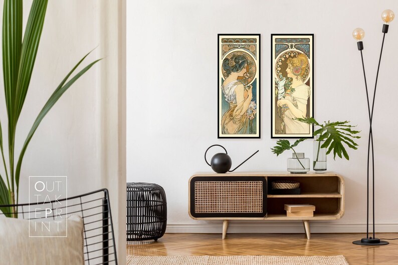 May include: Two framed art prints of women in vintage style dresses with floral accents. The prints are hanging on a white wall above a wooden cabinet with a woven rattan front.
