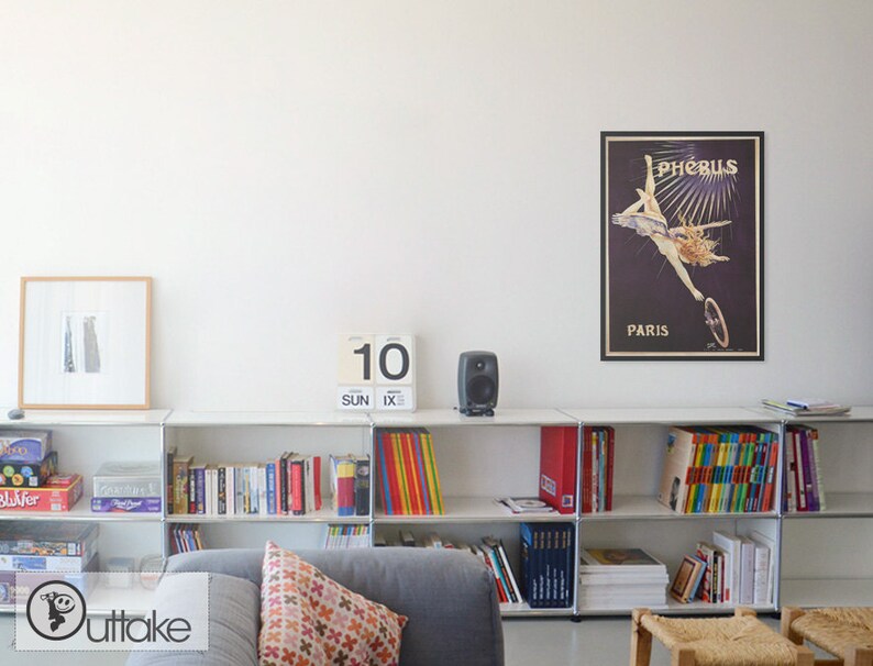 May include: A white bookshelf with books, games, and a calendar that says "10 SUN IX" on it. There is a framed poster on the wall that says "Ph&eacute;bus Paris" with a woman in a vintage dress riding a bicycle.