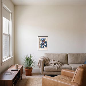 L'après framed art print, 16x22 inch, black wood frame, shown hanging in a living room