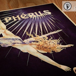 May include: A vintage poster with a woman with long blonde hair flying through the air with wings. The poster has a dark purple background with gold rays of light emanating from the center. The text "Ph&eacute;bus" is written in gold at the top of the poster.