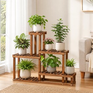 May include: A multi-tiered wooden plant stand with a dark brown finish, featuring six distinct levels for displaying potted plants. The stand holds various green houseplants and a small flowering plant in white ceramic pots of different shapes.