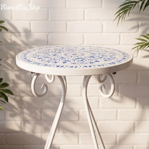 May include: A white metal side table with a round top featuring a blue and white mosaic design. The table has curved legs and decorative scrollwork. The table is approximately 24 inches in diameter.