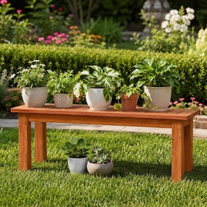 May include: A rectangular wooden bench with four legs, featuring four potted plants on its surface and two potted plants on the grass below. The plants include a white-flowered plant, a leafy green plant, and a succulent in various ceramic pots.