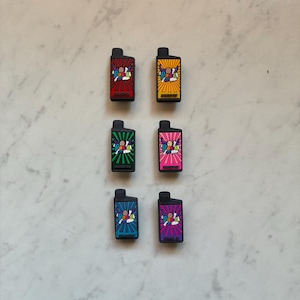 May include: Six colourful, rectangular accessories with a black top. Each features a cartoon graphic with the text "POP" and "BAR". The accessories are in red, yellow, green, pink, blue, and purple.