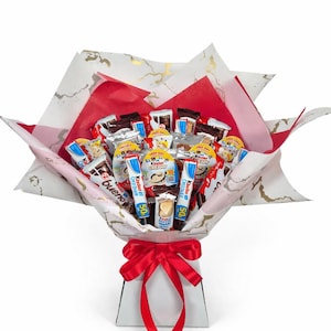 May include: A chocolate bouquet featuring a variety of chocolate bars and sweets, wrapped in patterned paper with red and gold details. The arrangement is presented in a white box and tied with a red ribbon.